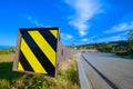 Bold yellow and black stripes mark the ends of a highway guardrail