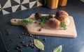 Boletes and bay boletes placed on a cutting board surrounded by spices,