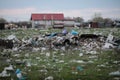 Piles of industrial and home waste lay on a field near inhabited houses