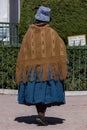 A bolivian woman wearing a woolen cap and a woven poncho walks arround the square in Copacabana, Bolivia