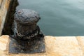 bollard or cast iron and steel mooring bollard on the edge of a harbor wharf with ropes for mooring ships