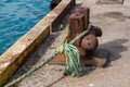 A bollard at a dockside with the rope of a boat tied around it to keep the boat moored to the jetty Royalty Free Stock Photo