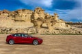 Bolnuevo, Murcia, Spain - February 7, 2020: panoramic view of a red Tesla Model 3 electric car with rock formation on the