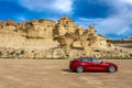 Bolnuevo, Murcia, Spain - February 7, 2020: panoramic view of a red Tesla Model 3 electric car with rock formation on the