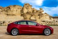 Bolnuevo, Murcia, Spain - February 7, 2020: side view of a red Tesla Model 3 electric car with rock formation on the mediterranean