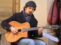 Street performer playing acoustic guitar. Busking on street concept. Italy