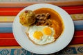 Bolon de verde with fried egg and meat stew