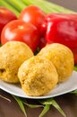 Bolon, an ecuadorian typical food on a white plate with a blurred tomato and pepper behind, over a green leaf