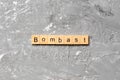 Bombast word written on wood block. bombast text on cement table for your desing, concept