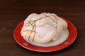 Bondage shibari raw chicken on red boarder plate on dark wood ba