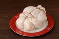 Bondage shibari raw chicken on red boarder plate on dark wood ba
