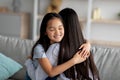 Bonding concept. Cute asian girl hugging her mother and smiling, sitting together on sofa, closeup portrait, free space