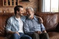 Happy elderly father adult son friends relax chat on couch