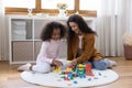 Happy preteen African American girl playing toys with mother. Royalty Free Stock Photo