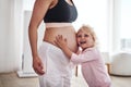 Bonding with her special little girl. an adorable little girl standing and hugging her pregnant mothers tummy in the