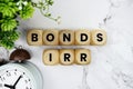 Bonds IRR Bond yield or return platform alphabet letters and alarm clock on marble background Royalty Free Stock Photo