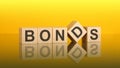 bonds word is made of wooden blocks lying on the yellow table, concept