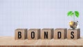 Bonds word in wooden blocks with coins stacked in increasing stacks. Bonds increasing concept, investment bond concept Raising