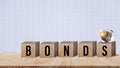Bonds word in wooden blocks with coins stacked in increasing stacks. Bonds increasing concept, investment bond concept Raising