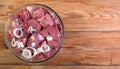 Boneless lamb steak cut into pieces, meat in a glass bowl on a wooden table, top view