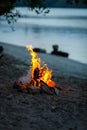 Bonfire is lit on the sandy beach of a lake