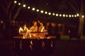 Bonfire burning in a garden a summer night, unknown people in the background.dark Royalty Free Stock Photo