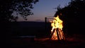 A bonfire burns in the middle of the night. Fire on the background of the river and mountains. Royalty Free Stock Photo