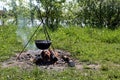 A bonfire with a hanging pot burns on the river