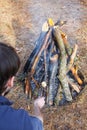 Bonfire in the spring forest on the background of withered grass. In the frame head, shoulder and arm of a man. Royalty Free Stock Photo