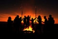 bonfire surrounded by the silhouettes of people laughing and dancing