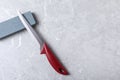 Boning knife, sharpening stone on grey background, flat lay