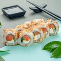 Bonito sushi roll sprinkled with tuna fish. With smoked salmon, cucumber and cream cheese. Decorated with greenery. In the Royalty Free Stock Photo