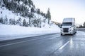 Bonnet big rig white semi truck transporting cargo in dry van semi trailer running on the winter dangerous slippery road with snow Royalty Free Stock Photo