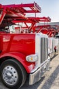 Bonnet red big rigs car hauler semi trucks with hydraulic semi trailers standing in row on the industrial parking lot Royalty Free Stock Photo