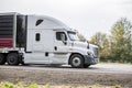 Bonnet white big rig semi truck tractor transporting frozen cargo in refrigerator semi trailer driving on the straight road Royalty Free Stock Photo