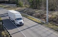 Bonnet white big rig semi truck transporting industrial cargo in dry van semi trailer running on the one way highway road Royalty Free Stock Photo