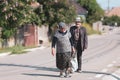 An elderly couple on an empty street in a village in rural Romania on a hot bright summer day