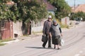 An elderly couple on an empty street in a village in rural Romania on a hot bright summer day