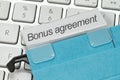 Bonus agreement as a term on a tab on a blue hanging file on a computer keyboard Royalty Free Stock Photo