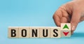 Bonus is going up or vice down. Hand is turning wooden cubes a dice and changes the direction of an arrow symbolizing Royalty Free Stock Photo