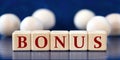 BONUS - word on wooden cubes on a blue background with wooden balls