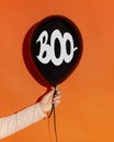 Black balloon with text in woman hand on orange background Royalty Free Stock Photo