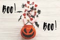 Boo! text sign. Happy Halloween. Jack o Lantern bucket with holiday candy, bats, spiders, skulls on white rustic wooden Royalty Free Stock Photo