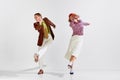 Boogie-woogie. Young man and woman in stylish clothes dancing retro dance against grey studio background