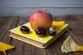 A book apple yellow leaves chestnut on wooden background