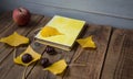 A book apple yellow leaves chestnut on wooden background