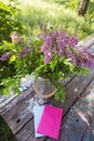 The book, a beautiful bouquet of lilacs is on an old table. Close-up