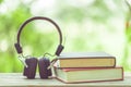 Book and black headphone on wooden table with abstract green nature blur background. Reading and education concept Royalty Free Stock Photo