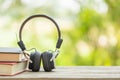 Book and black headphone on wooden table with abstract green nature blur background. Reading and education concept Royalty Free Stock Photo