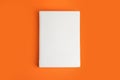 Book with blank cover on orange, top view